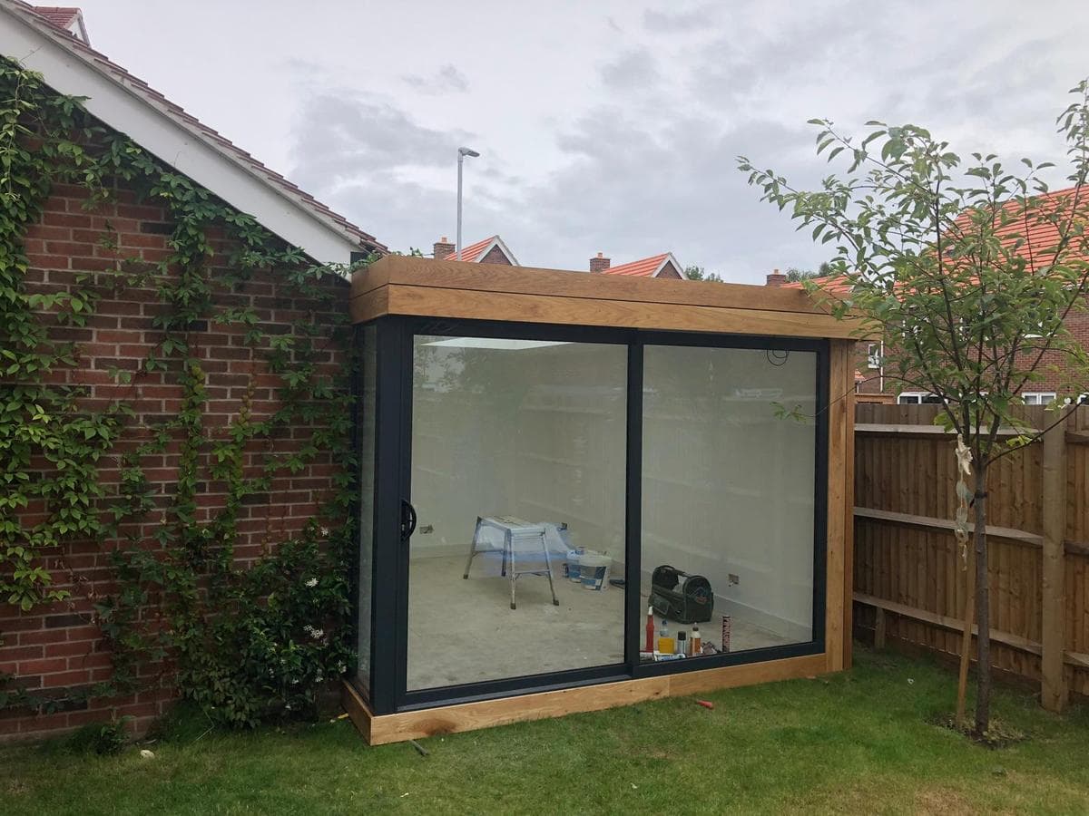 Brick garden room with sliding doors seen from across the garden